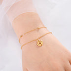 Bracelet doré avec petite breloque spirale or